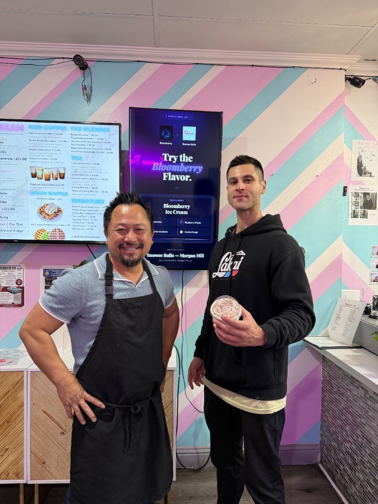 Bloomberry founder Sadok Hasan with Snowee Rolls owner β the Bloomberry digital advertisement visible on the in-store display screen behind them